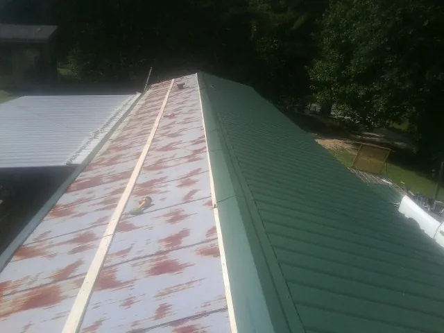 Old rusted panels beside newly installed green metal roofing in Marietta